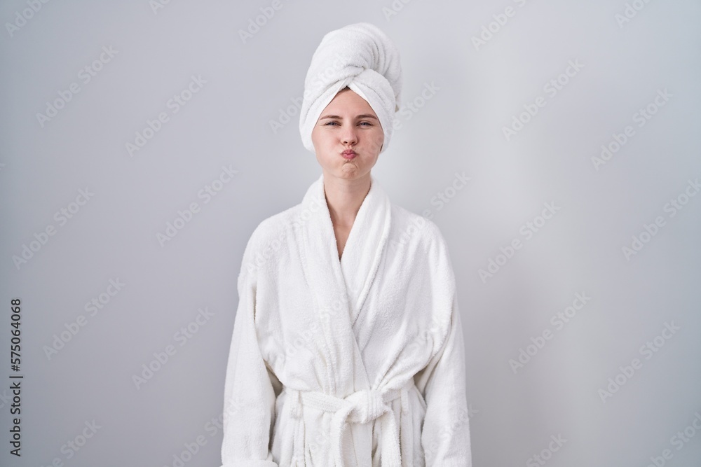 Blonde caucasian woman wearing bathrobe puffing cheeks with funny face. mouth inflated with air, crazy expression. Blonde caucasian woman wearing bathrobe puffing cheeks with funny face. mouth inflated with air, crazy expression.