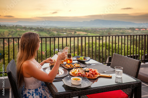 Elegant woman in luxury outdoor restaurant with sunset mountain view © TravelMedia