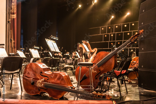 stringed musical instruments of the symphony orchestra lie on the stage before the concert rehearsal. Violins cellos double basses on an empty stage