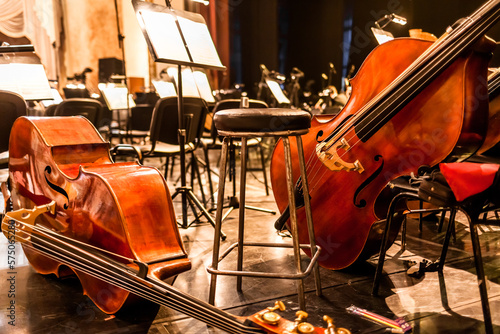 stringed musical instruments of the symphony orchestra lie on the stage before the concert rehearsal. Violins cellos double basses on an empty stage