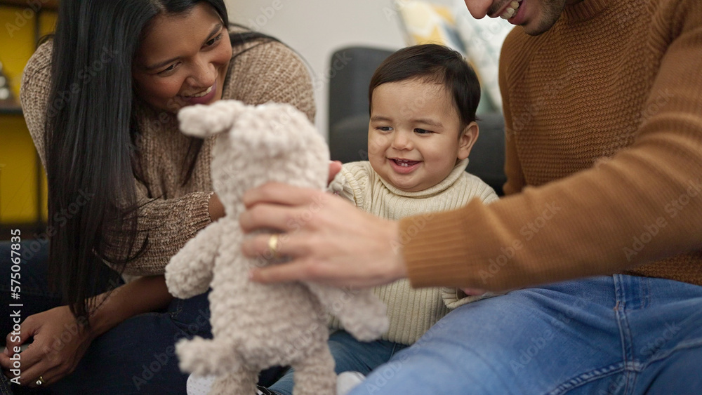 Couple and son playing with teddy bear sitting on floor at home Couple and son playing with teddy bear sitting on floor at home