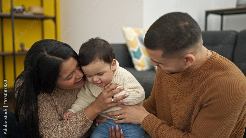 Couple and son hugging each other sitting on floor at home Couple and son hugging each other sitting on floor at home