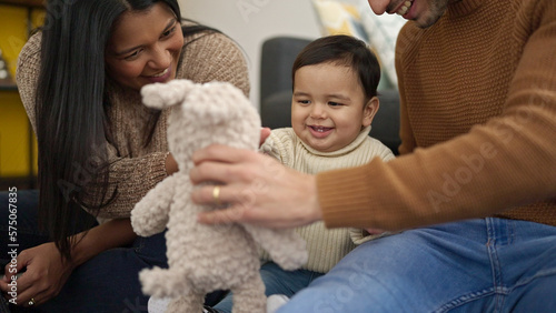 Couple and son playing with teddy bear sitting on floor at home