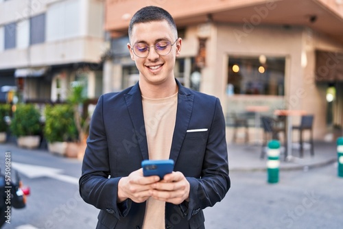 Young hispanic man executive smiling confident using smartphone at street