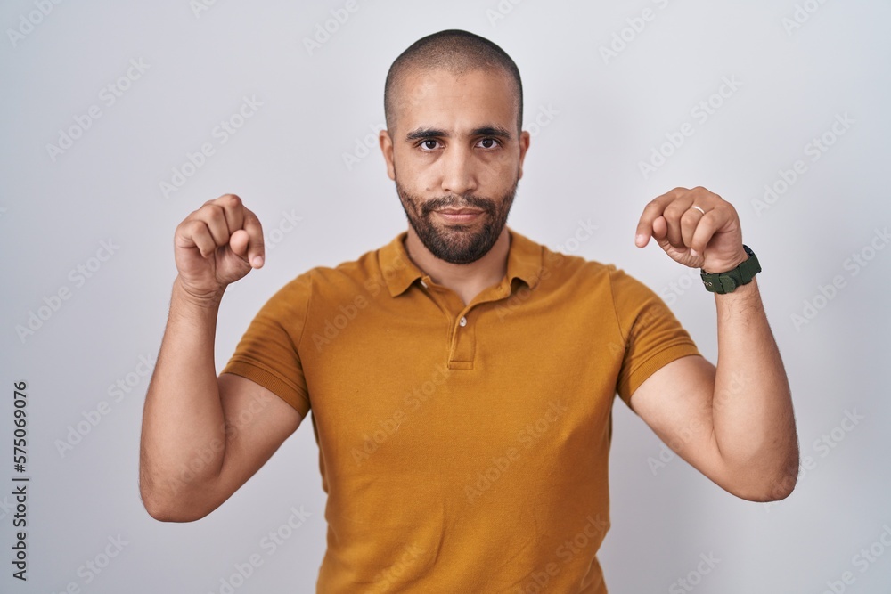 Fototapeta premium Hispanic man with beard standing over white background pointing down looking sad and upset, indicating direction with fingers, unhappy and depressed.