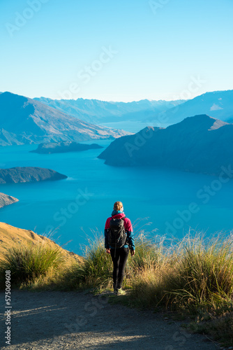 Frau und Wanderin mit Ausblick über Berge und Seen bei Sonnenschein und blauem Himmel in Neuseeland. © hannesheigl