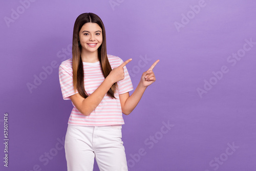 Photo of pretty sweet young lady wear striped pink white t-shirt pointing two fingers empty space isolated violet color background © deagreez