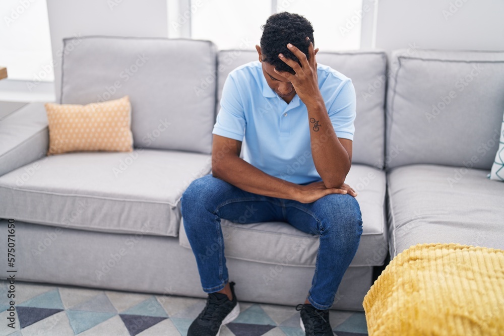 Young latin man stressed sitting on sofa at home Young latin man stressed sitting on sofa at home