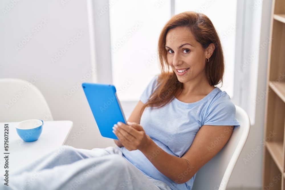 Young woman using touchpad and drinking coffee at home Young woman using touchpad and drinking coffee at home