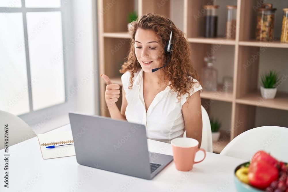 Young caucasian woman wearing call center agent headset working from home smiling happy and positive, thumb up doing excellent and approval sign Young caucasian woman wearing call center agent headset working from home smiling happy and positive, thumb up doing excellent and approval sign