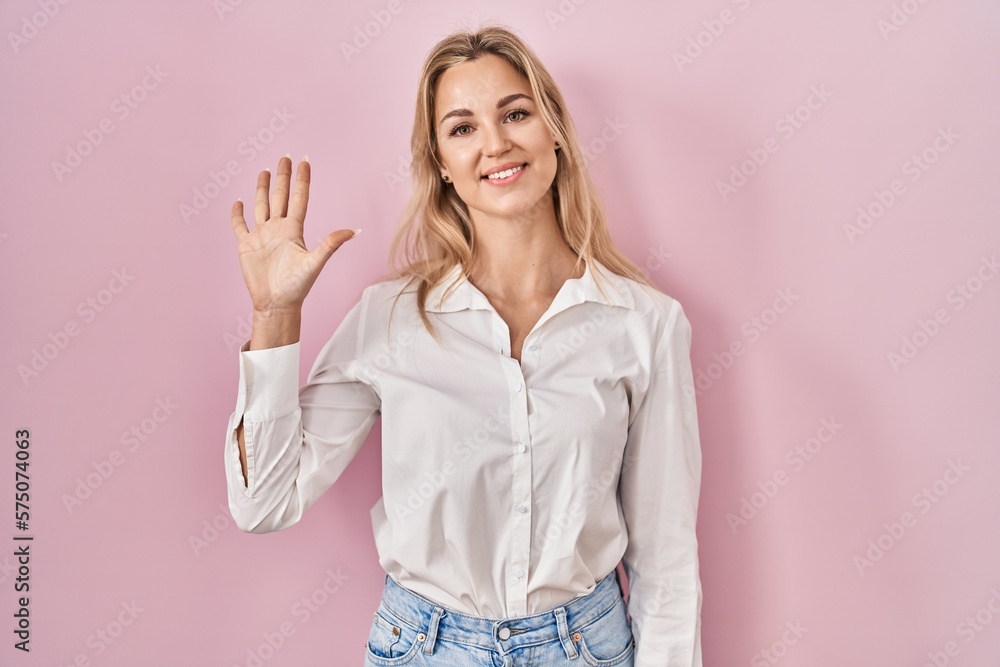 Young caucasian woman wearing casual white shirt over pink background showing and pointing up with fingers number five while smiling confident and happy. Young caucasian woman wearing casual white shirt over pink background showing and pointing up with fingers number five while smiling confident and happy.