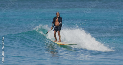 Mature man surfer paddle board surfing ocean waves