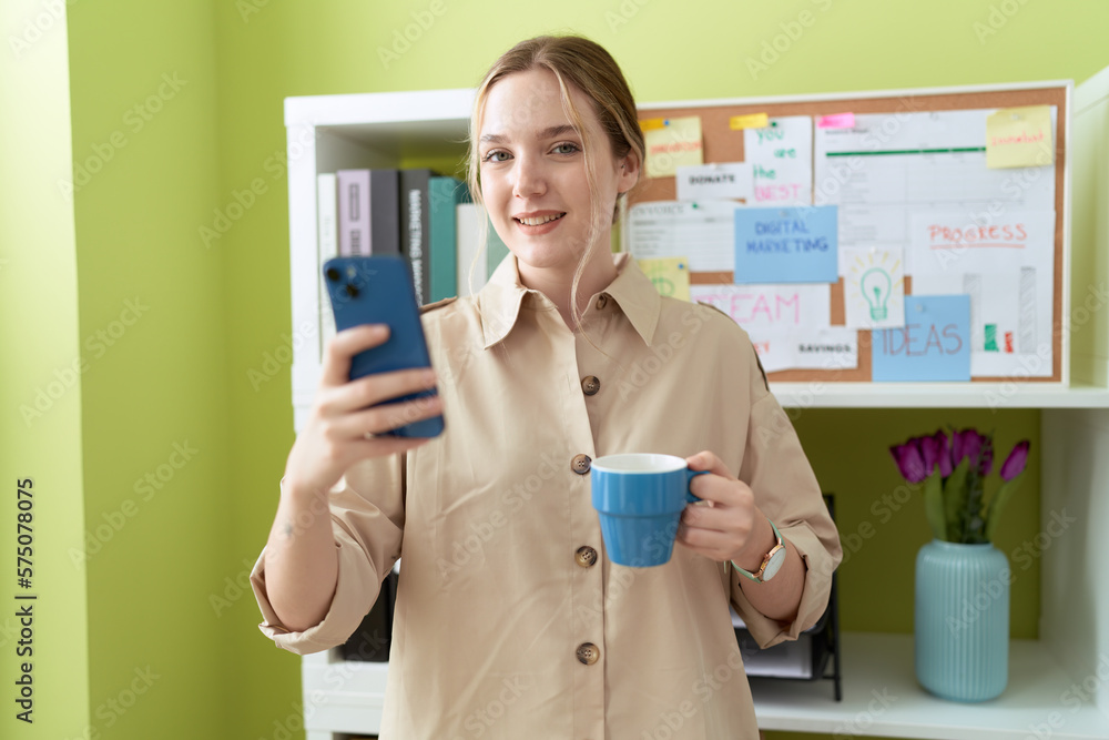 Young caucasian woman business worker using smartphone drinking coffee at office Young caucasian woman business worker using smartphone drinking coffee at office