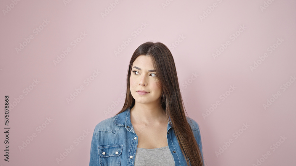 Fototapeta premium Young beautiful hispanic woman looking to the side with serious expression over isolated pink background