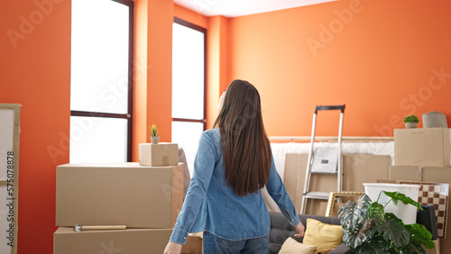 Young beautiful hispanic woman standing on back view at new home