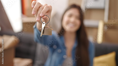 Young beautiful hispanic woman smiling confident holding key at new home