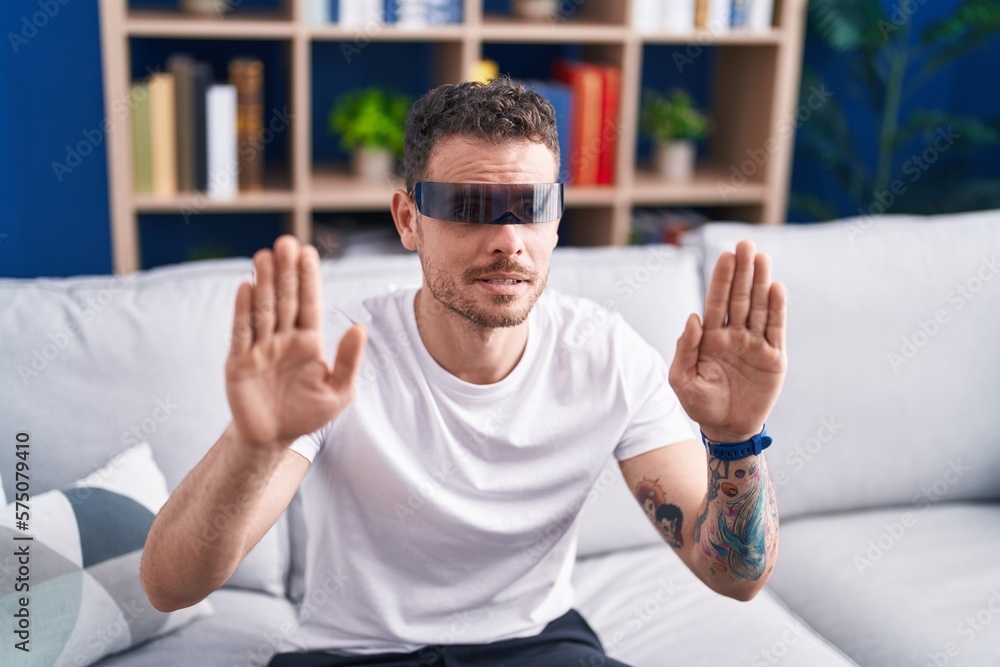 Young hispanic man playing video game using virtual reality glasses at home Young hispanic man playing video game using virtual reality glasses at home