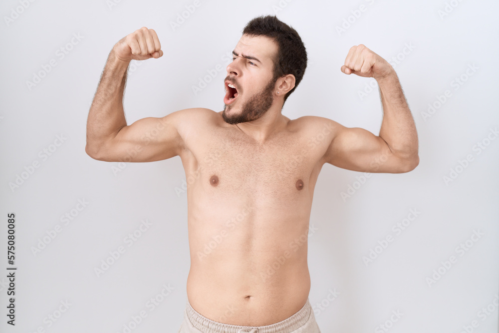 Young hispanic man standing shirtless over white background showing arms muscles smiling proud. fitness concept. Young hispanic man standing shirtless over white background showing arms muscles smiling proud. fitness concept.
