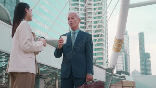 Asian senior mature middle aged businessman and young businesswoman having a discussion and coffee in modern city