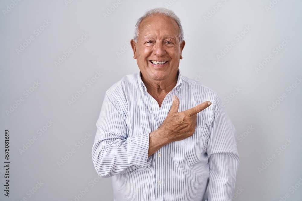 Senior man with grey hair standing over isolated background cheerful with a smile on face pointing with hand and finger up to the side with happy and natural expression Senior man with grey hair standing over isolated background cheerful with a smile on face pointing with hand and finger up to the side with happy and natural expression