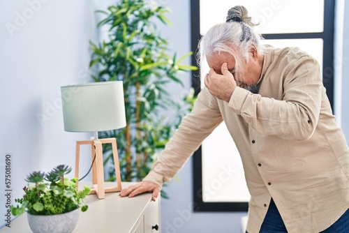 Middle age grey-haired man suffering dizzy standing at home photo
