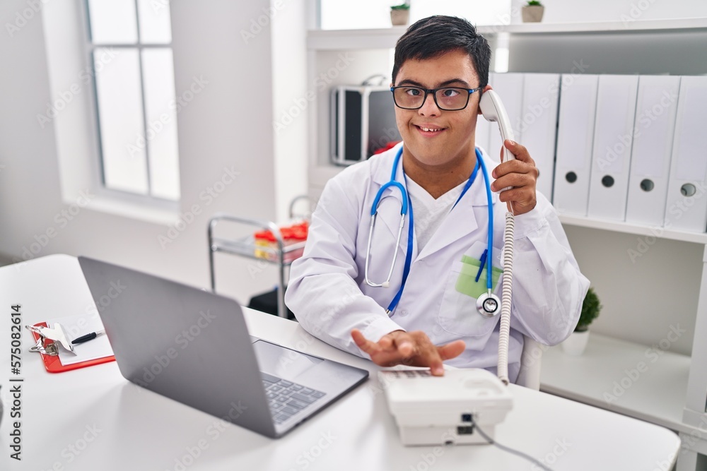 Down syndrome man wearing doctor uniform talking on the telephone at clinic Down syndrome man wearing doctor uniform talking on the telephone at clinic