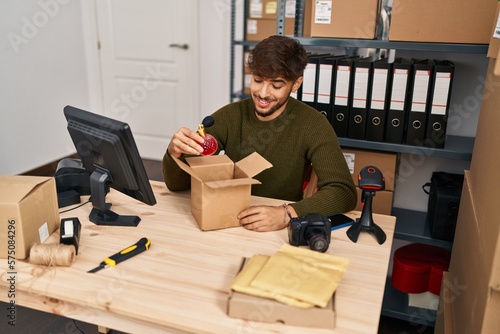 Young arab man ecommerce business worker packing perfume at office