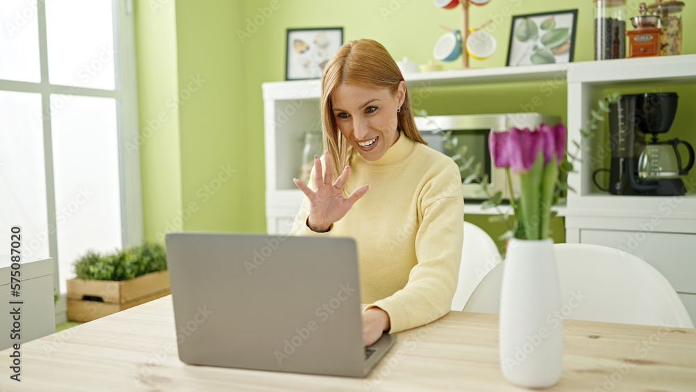 Young blonde woman having video call sitting on table at home Young blonde woman having video call sitting on table at home