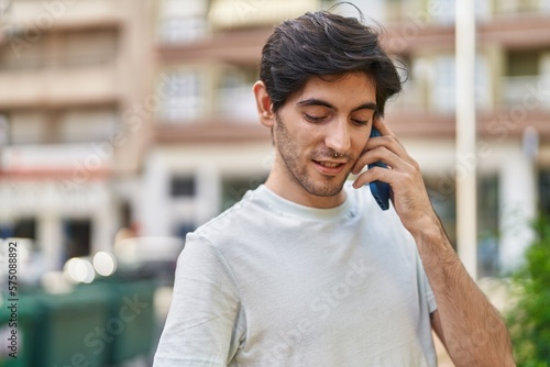 Young hispanic man talking on the smartphone with relaxed expression at street