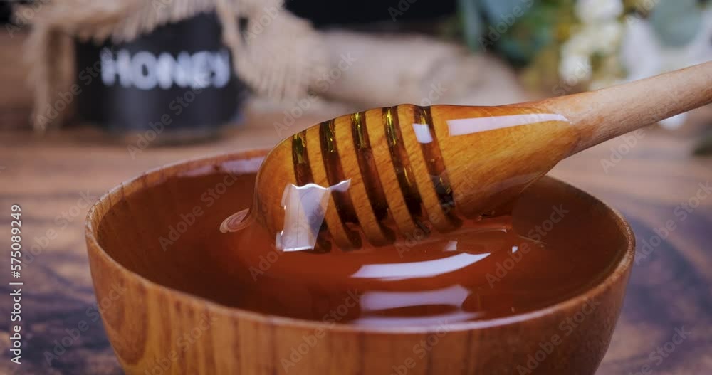 Honey spoon coming out of the bowl full of honey in slow motion. Honey