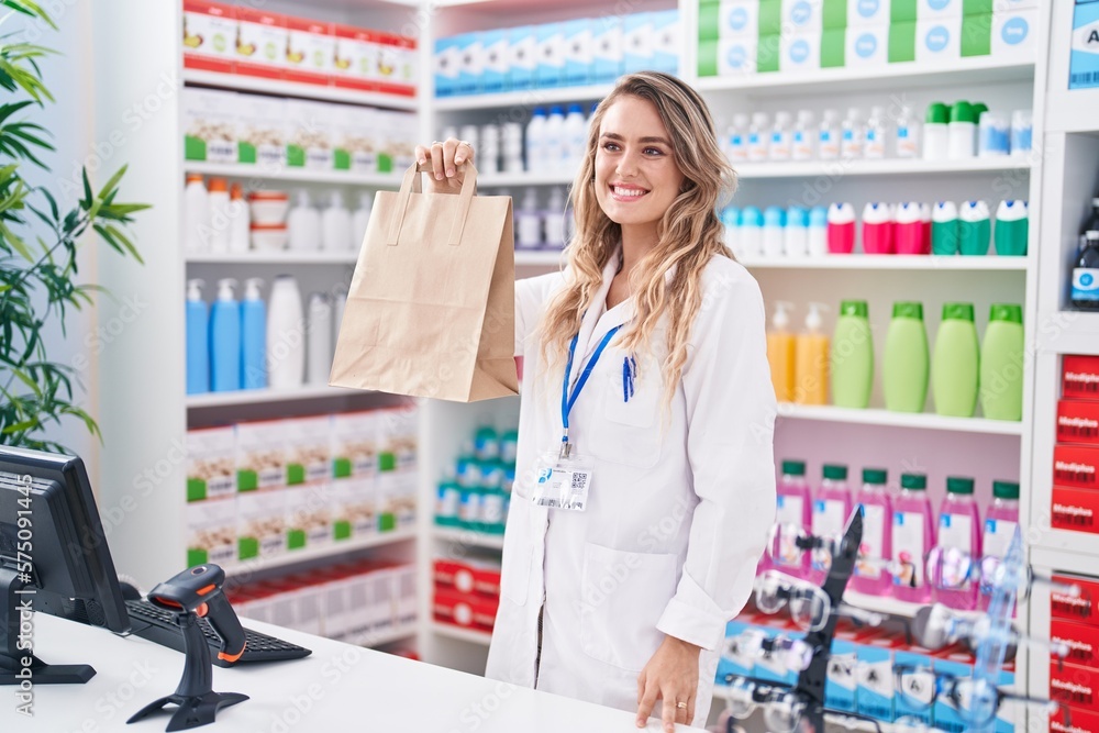 Young blonde woman pharmacist smiling confident holding shopping bag at pharmacy Young blonde woman pharmacist smiling confident holding shopping bag at pharmacy