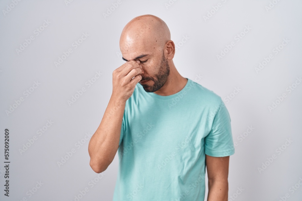 Middle age bald man standing over white background tired rubbing nose and eyes feeling fatigue and headache. stress and frustration concept. Middle age bald man standing over white background tired rubbing nose and eyes feeling fatigue and headache. stress and frustration concept.