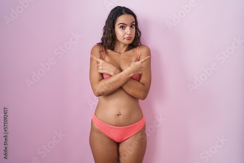 Young hispanic woman wearing lingerie over pink background pointing to both sides with fingers, different direction disagree