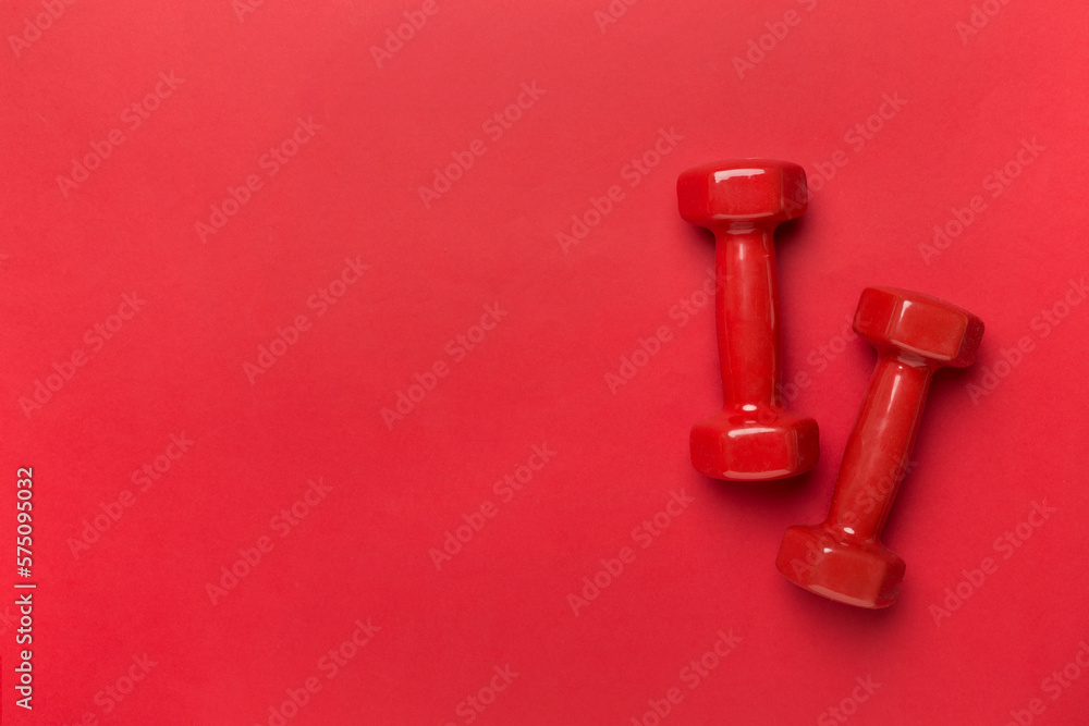 Red dumbbells on color background, top view Red dumbbells on color background, top view