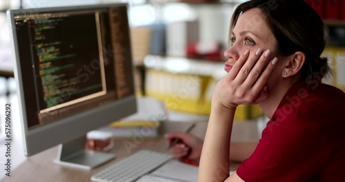 Bored woman sits at computer in office and looks into distance unable to work