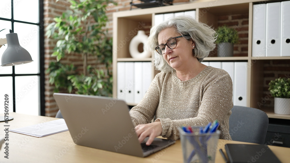 Middle age woman with grey hair business worker using laptop working at office Middle age woman with grey hair business worker using laptop working at office