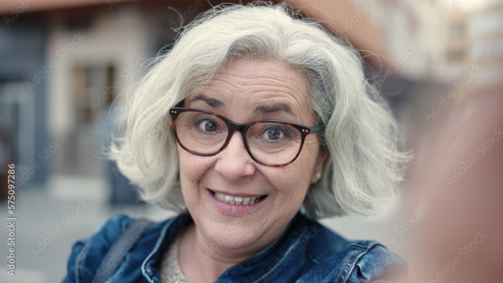 Middle age woman with grey hair smiling confident having video call at street Middle age woman with grey hair smiling confident having video call at street