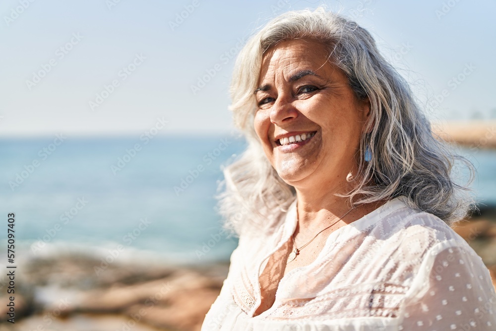 Middle age woman smiling confident standing at seaside Middle age woman smiling confident standing at seaside
