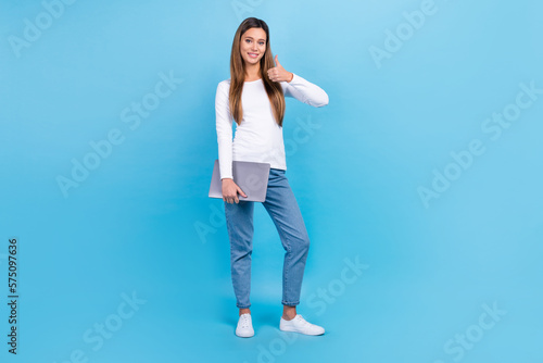 Full length photo of adorable confident woman wear white shirt thumb up holding modern gadget isolated blue color background