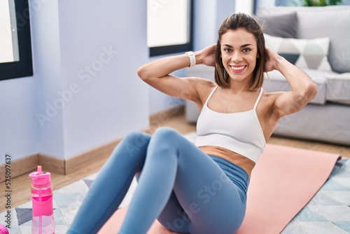 Young beautiful hispanic woman training abs exercise at home