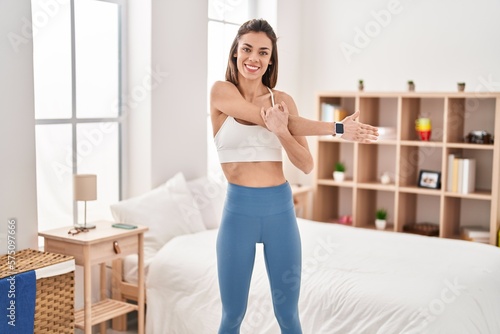 Young beautiful hispanic woman smiling confident stretching arm at bedroom