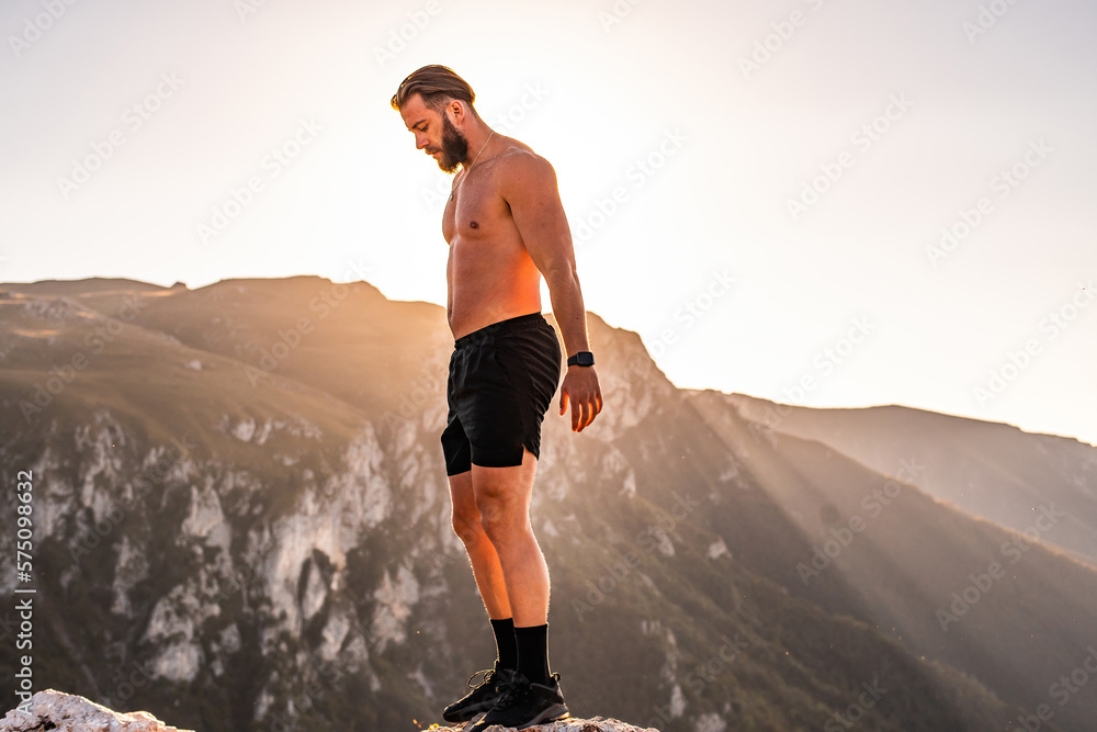 An athlete rests on top of a mountain after exhausting running training.