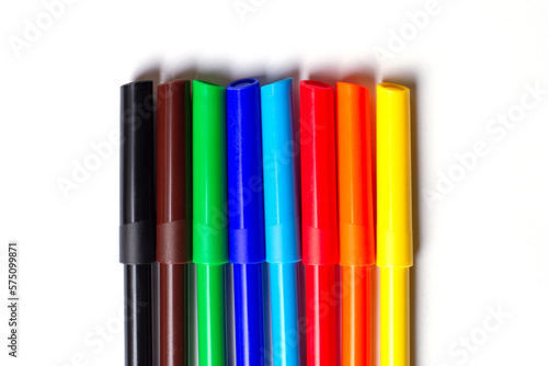 Markers of different colors lie in a row. On a white background.