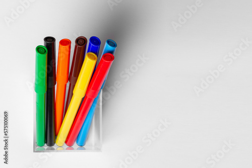 Felt pens of different colors are in a glass. On a white background.