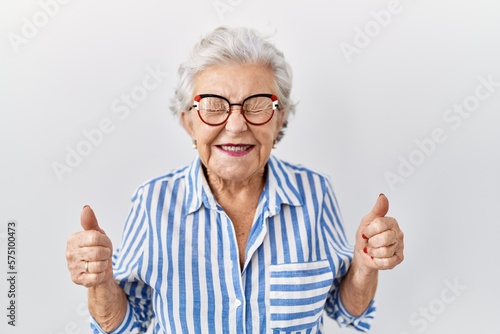 Senior woman with grey hair standing over white background excited for success with arms raised and eyes closed celebrating victory smiling. winner concept.