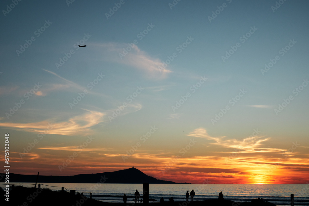 Obraz premium silhouette of several people walking on the beach enjoying the sunset