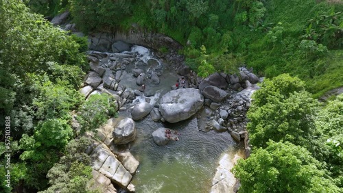 Veiws of a mountain river pool at the bottom of a Puerto Rican rainforest, with people enjoying the afternoon.  photo