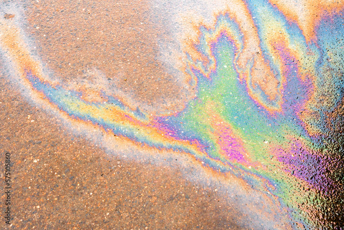 Oil slick on the asphalt road background. Rainbow gasoline oil spill on the pavement as a texture or background.