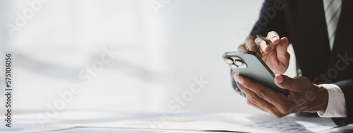 Business man looking at financial information from a mobile phone, he is checking company financial documents, he is an executive of a startup company. Concept of financial management.