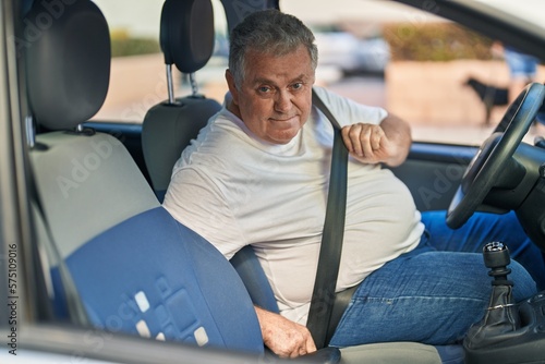 Middle age grey-haired man smiling confident wearing car belt at street © Krakenimages.com